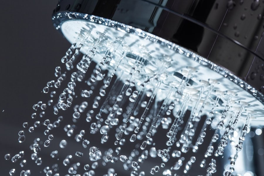 Water flowing out of showerhead to represent information about water heater repairs.